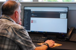 A person sitting in front of their computer, looking at ERP software. 